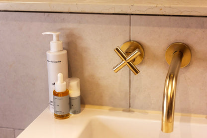 Signature Glow produkter i brug. Stående ved vask med messingarmatur. Enkelt og effektivt hudplejesæt til mænd.